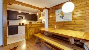 Eine Küche mit Holzschränken, einer zentralen Kochinsel, Pendelleuchten und einem Wandbild.
