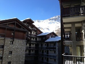 A traditional mountain lodge with stone and wood architecture, multiple balconies, and a view of snow-covered mountains. - Comfortable apartment at ski slopes - 6 guests (Val-d'Isère)