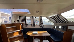 A boat interior with a dining area, a cushioned bench, and a small table.