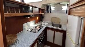 A compact kitchen with a gas stove, sink, and a refrigerator.