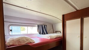 A compact, single-bed RV interior with a window, curtains, and a door.