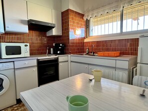 Ett kompakt kök med mikrovågsugn, kaffebryggare och diskho.
