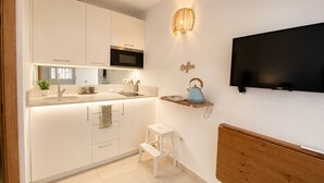 A modern kitchen with a built-in microwave, a sink, and a small stool. - Beach Getaway with a Pool and Parking (AN)