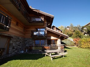 A wooden cabin with a stone foundation, a balcony, and a wooden deck. - Chalet exceptional view - 6 guests (Les Deux Alpes)