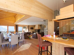 Ein geräumiges Wohnzimmer mit Holzbalkendecke, Steinwand und Blick ins Freie.