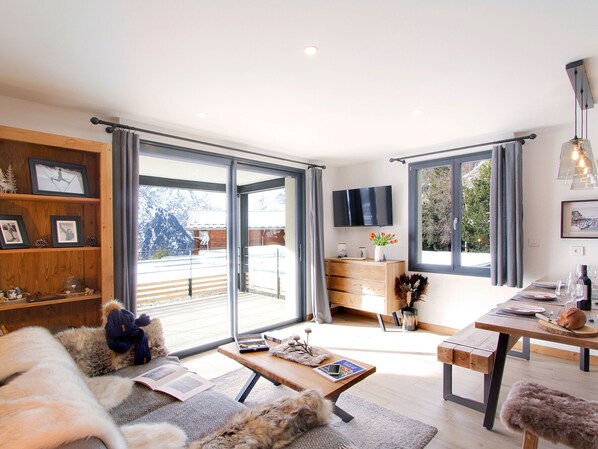 Ein modernes Wohnzimmer mit einer Couch, einem Couchtisch und einem Essbereich mit einem Holztisch und Bänken.