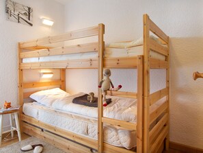 A bunk bed with a wooden frame, a bedside table with a lamp, and a wall-mounted picture. - Bright apartment at the foot of the slopes - 4 guests (Les Deux Alpes)