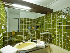 Ein Badezimmer mit Waschbecken, Spiegel und grünen Fliesen.