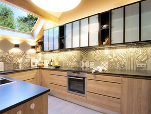 Een moderne keuken met houten kastjes, een inbouwoven en een dakraam.