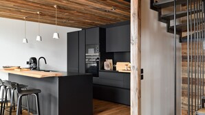 Una cocina moderna con techo de madera, armarios negros y una isla central con taburetes de bar.