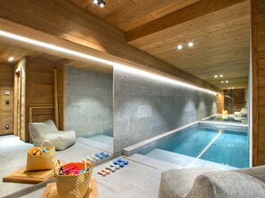 Un espace de bien-être avec piscine, plafond en bois et murs en pierre.