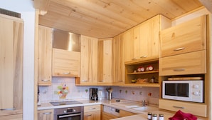 Eine Küche mit Holzschränken, einer Mikrowelle, einer Kaffeemaschine und einem Holzschnittbrett.