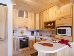 Eine Küche mit Holzschränken, einer Mikrowelle, einer Kaffeemaschine und einem Holzschnittbrett.