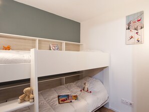 A bunk bed room with a shelf above the lower bunk, a wall-mounted painting, and a power outlet. - Apartment with terrace - 4 guests (Les Deux Alpes)
