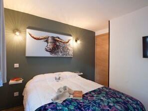 A hotel room with a bed, a wall-mounted artwork of a bull, and a wooden door. - Apartment with terrace - 4 guests (Les Deux Alpes)