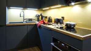 Una cocina moderna con armarios oscuros, encimera de acero inoxidable, horno integrado y microondas.