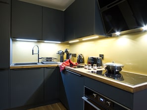 A modern kitchen with dark cabinetry, a stainless steel countertop, a built-in oven, and a microwave. - Apartment with terrace - 4 guests (Les Deux Alpes)