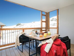 A balcony with a wooden table, chairs, and a view of a snowy mountain. - Apartment with slope view - 5 stars (Huez)