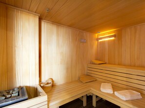 A sauna room with wooden benches, a bench heater, and towels. - Charming apartment in the heart of Les Deux Alpes (Les Deux Alpes)