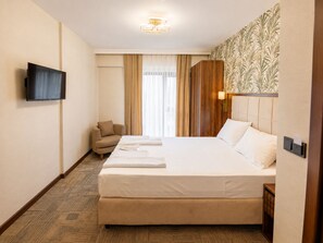 A hotel room with a bed, a TV, a chair, and a window with curtains. - THE WISDOM HOTEL (İstanbul)