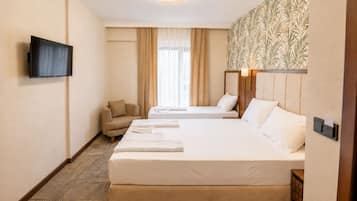 Une chambre d’hôtel avec deux lits, une télévision, une chaise et un mur décoré de motifs.