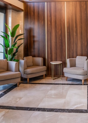 Un hall con tres sillones, una pequeña mesa redonda y una planta grande.