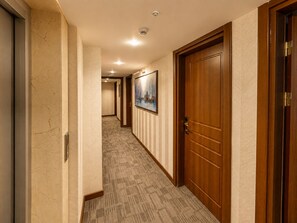 Un pasillo de hotel con piso alfombrado, puertas de madera y un cuadro en la pared.