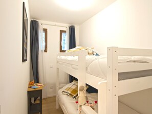 A bunk bed room with a small table and a window with curtains. - Beautifully decorated apartment, calm - 4 guests (Les Deux Alpes)