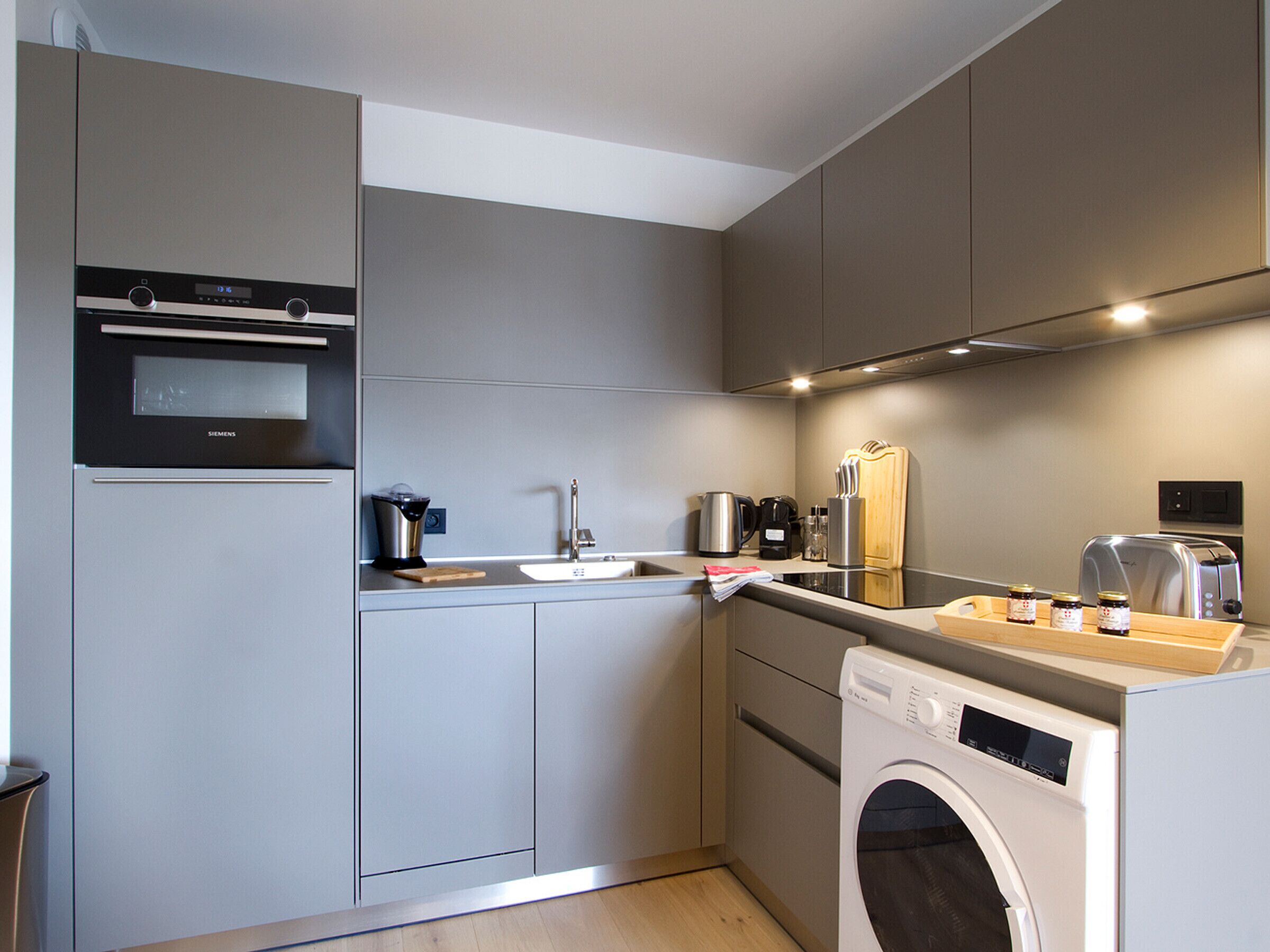 A modern kitchen with a built-in oven, a sink, a coffee maker, and a dishwasher.