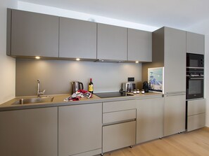 A modern kitchen with a built-in oven, a coffee maker, and a wine bottle. - Spacious apartment ski-in/ski-out - 6 guests (Huez)