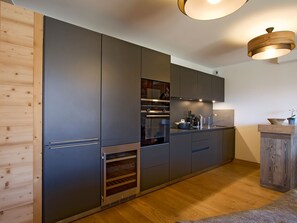 A modern kitchen with built-in appliances, wooden accents, and a wooden floor. - Spacious apartment ski-in/ski-out - 8 guests (Huez)