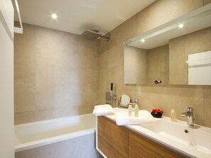 A modern bathroom with a bathtub, a sink, and a large mirror. - Spacious apartment ski-in/ski-out - 8 guests (Huez)