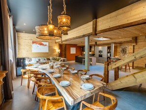 A spacious dining area with a long wooden table set for a meal, surrounded by wooden chairs. - Spacious chalet, parking - 14 guests (Les Deux Alpes)