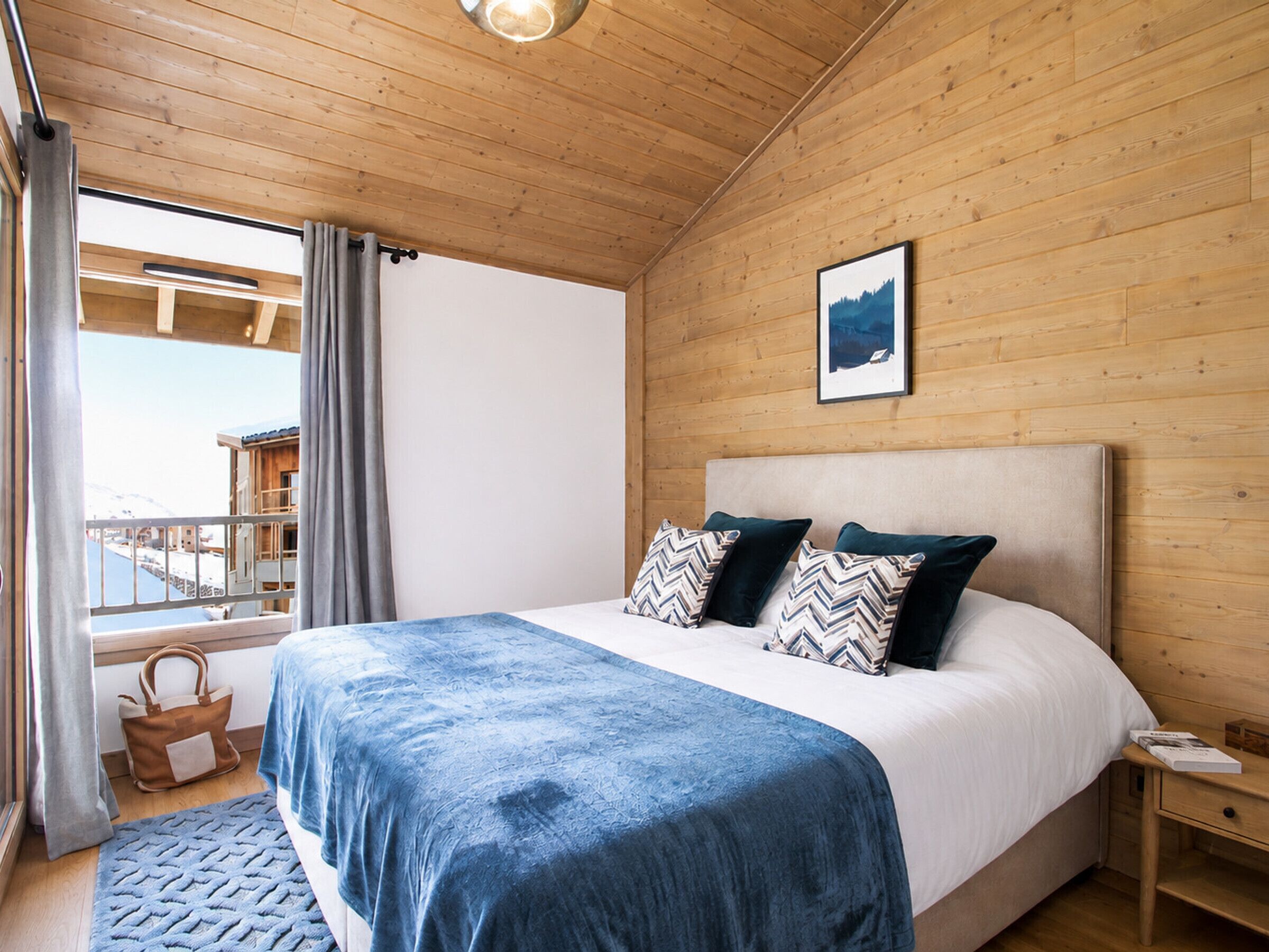 Ein Schlafzimmer mit Bett, Nachttisch, Fenster mit Vorhängen und einem Bild an der Wand.