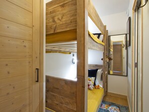 A room with a bunk bed, a mirror, and a door. - Bright duplex apartment at the slopes (Huez)
