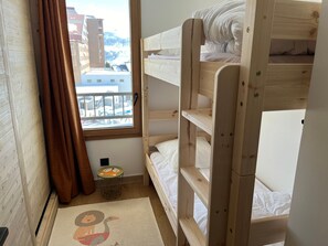 A bunk bed room with a view of buildings outside the window. - Top-floor apartment, piste view - 6 guests (Huez)