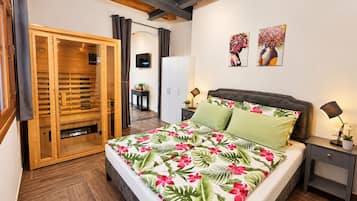 A bedroom with a bed, a wardrobe, a television, and artwork on the wall.