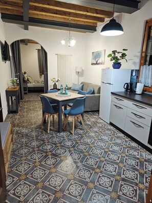 Un espacio habitable compacto con comedor, kitchenette y un dormitorio pequeño.