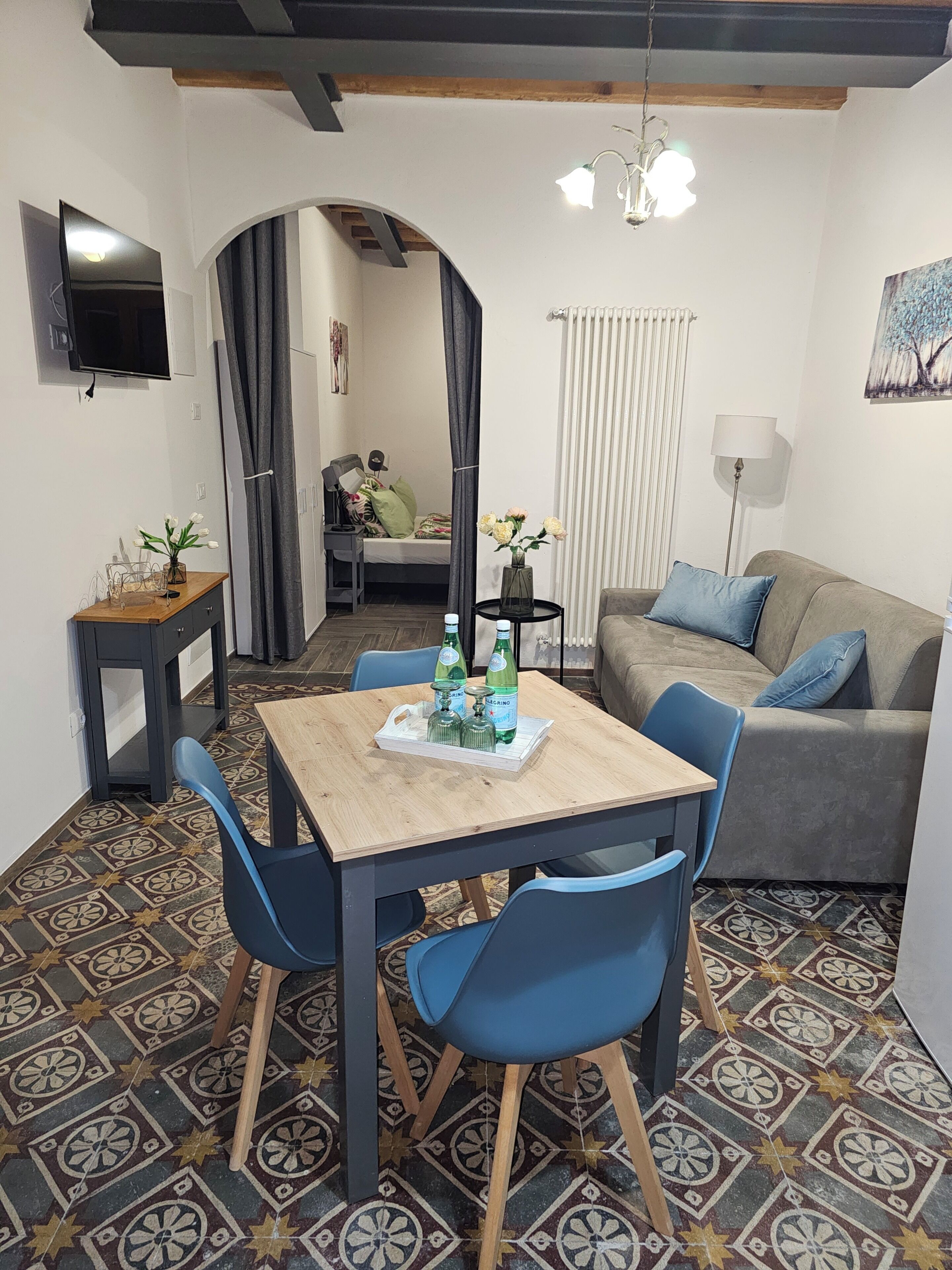 A compact living space with a dining area, a sofa, and a TV mounted on the wall.