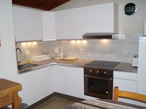 A compact kitchen with white cabinets, a stainless steel sink, a coffee maker, and a built-in oven. - Spacious apartment, ski-in ski-out access (Les Deux Alpes)