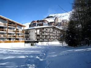A multi-story hotel with balconies and a ski slope in the background. - Spacious apartment, ski-in ski-out access (Les Deux Alpes)