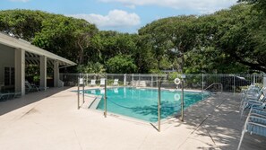 Ein Swimmingpool mit umzäuntem Deckbereich, Liegestühlen und einer überdachten Sitzgelegenheit.