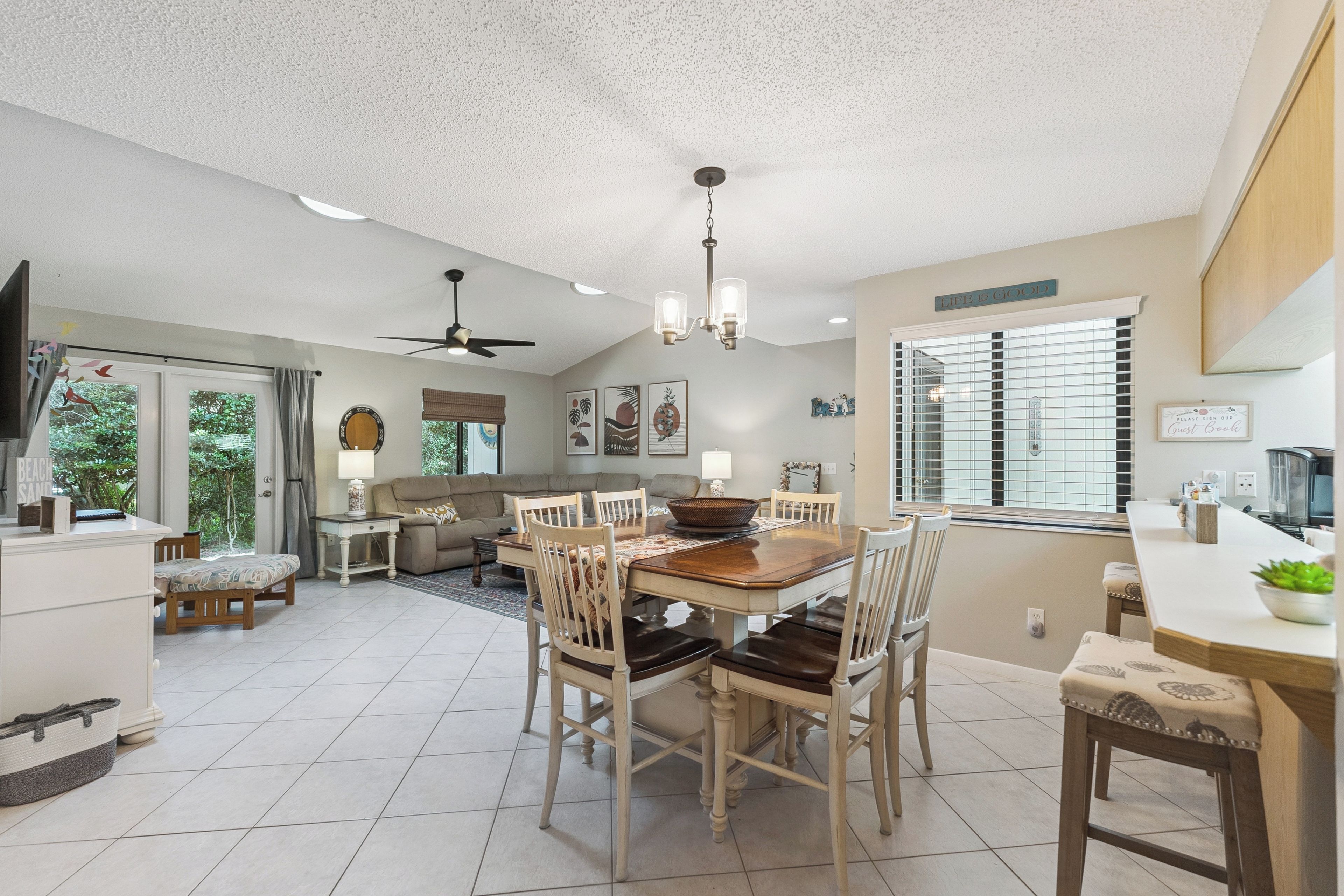 A spacious living area with a dining table, chairs, a sofa, and a ceiling fan.
