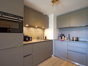 A modern kitchen with built-in appliances, a coffee maker, and a toaster. - Spacious apartment with garden - 5 guests (Huez)