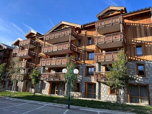 Ein mehrstöckiges Hotel mit Balkonen, Steinfassade und einem Parkplatz.