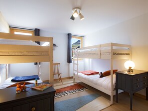 Ein Schlafraum mit Etagenbetten, Schreibtisch, Stuhl und Lampe.
