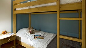 Ein Etagenbett mit unterem Bett und Schreibtisch, ein Stuhl, ein Stofftier und eine Zeitschrift.