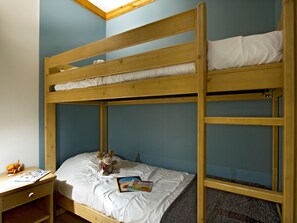 Ein Etagenbett mit unterem Bett und Schreibtisch, ein Stuhl, ein Stofftier und eine Zeitschrift.