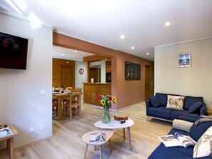 Ein Wohnzimmer mit einer Couch, einem Couchtisch und einem Essbereich mit Holzmöbeln.