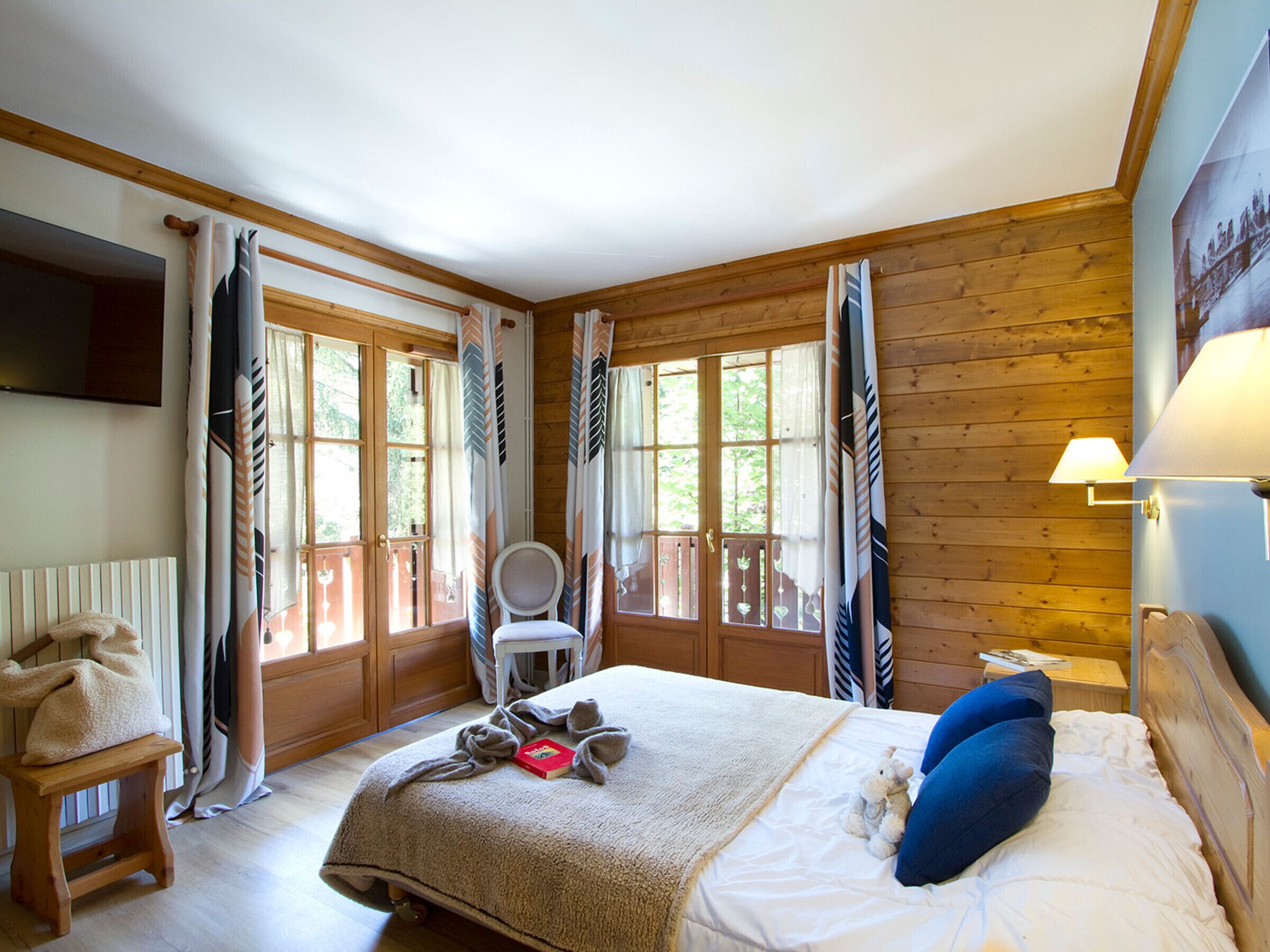 Une pièce avec un lit, une chaise, une lampe et une fenêtre avec des rideaux.